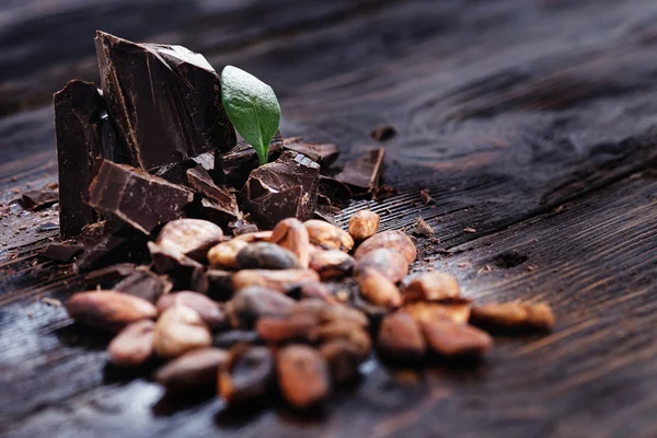 Trozos de chocolate con granos de cacao en una mesa de madera — Foto de Stock