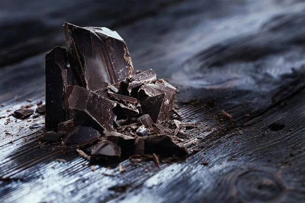 Pedaços de chocolate em uma mesa de madeira — Fotografia de Stock