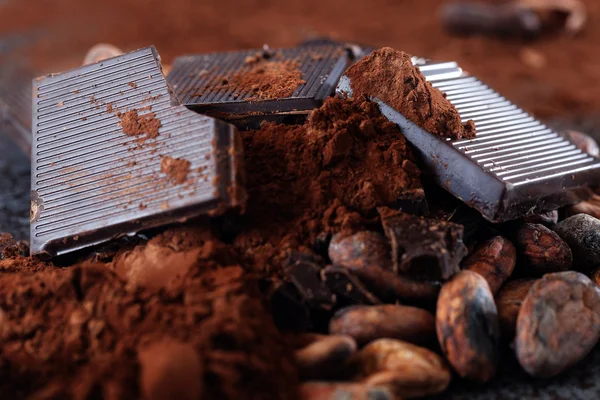 Chocoladestukjes met stukjes cacaobonen op een houten tafel — Stockfoto