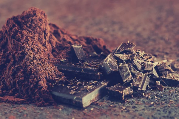 Pedaços de chocolate e cacau em pó em uma mesa de pedra — Fotografia de Stock