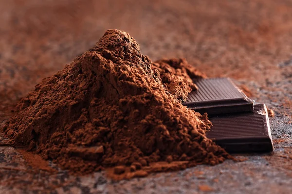 Chocoladestukjes en poeder van de cacao op een stenen tafel — Stockfoto