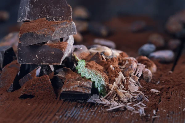 Trozos de chocolate negro y cacao en polvo sobre una mesa de madera — Foto de Stock