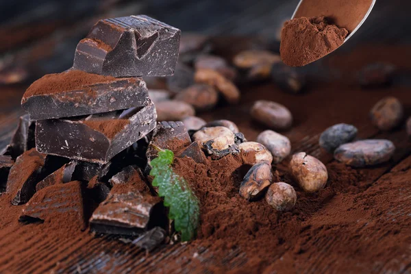 Dark chocolate pieces and cocoa powder on a wooden table