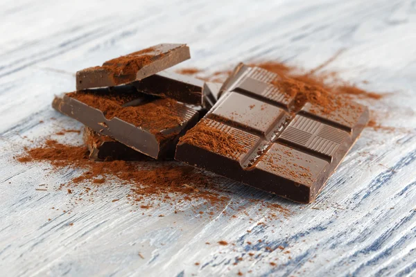 Chocolate escuro quebrado em uma mesa de madeira — Fotografia de Stock