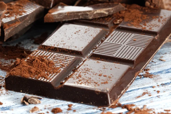 Chocolate escuro quebrado em uma mesa de madeira — Fotografia de Stock