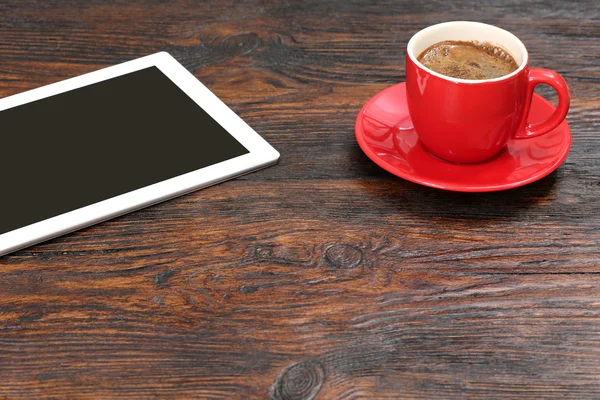 Taza de café y tableta en mesa de madera — Foto de Stock