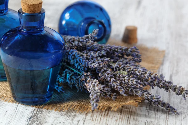 Lavendelöl in einer Glasflasche vor einem Hintergrund frischer Blumen — Stockfoto