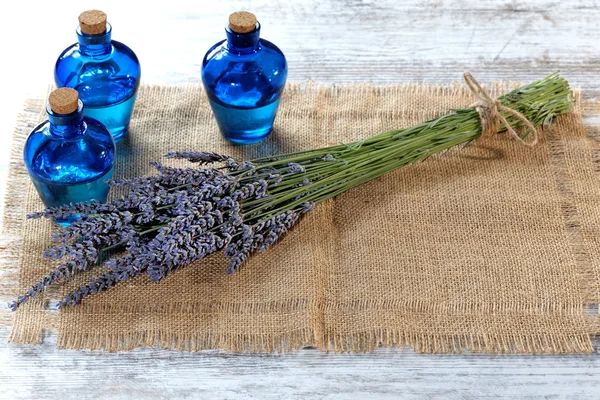 Lavendelöl in einer Glasflasche vor einem Hintergrund frischer Blumen — Stockfoto