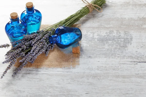 Lavendelöl in einer Glasflasche vor einem Hintergrund frischer Blumen — Stockfoto