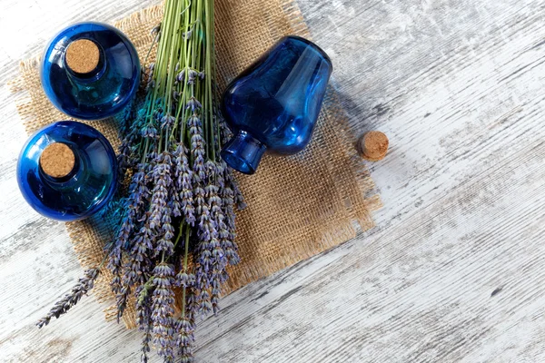 Lavendelöl in einer Glasflasche vor einem Hintergrund frischer Blumen — Stockfoto