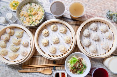 Steamed xiaolongbao and steamed dumplings served in a traditional steaming basket  clipart