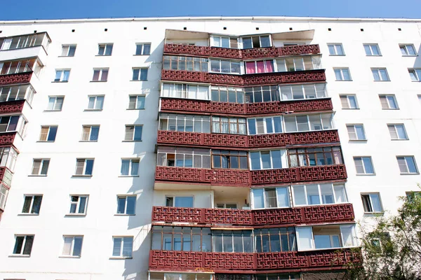 The facade of a multi-storey residential building, the balconies are painted with brown paint