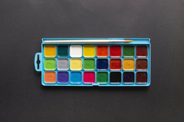 Açık renkli suluboya resimler ve siyah arka planda çıplak ambalajda boya fırçası. Üst Görünüm, Düz Yat