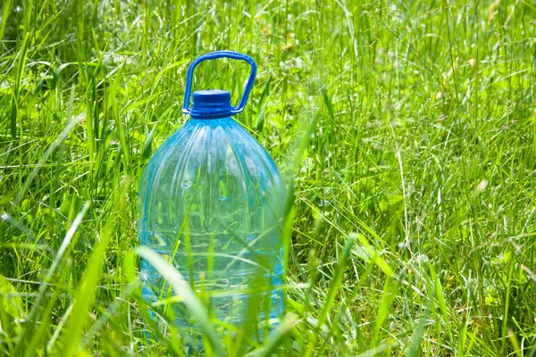 Large plastic bottle with water in green grass