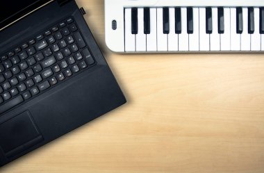 Bilgisayar dizüstü bilgisayarı ve masada klavyesi olan elektrikli sentezleyici. Metin için yer