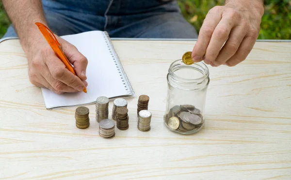 Äldre Man Räknar Små Mynt Och Skriver Ner Dem Anteckningsbok — Stockfoto