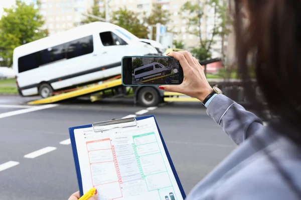 Kvinna försäkring agent filmer trasiga minibuss på smartphone — Stockfoto