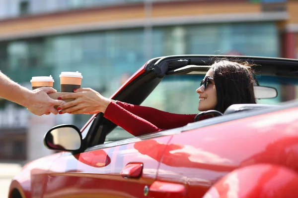 Frau sitzt im Cabrio und bekommt Kaffee serviert. — Stockfoto