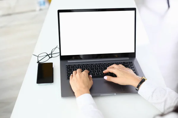 Женские руки на клавиатуре ноутбука, которая стоит на столе. — стоковое фото