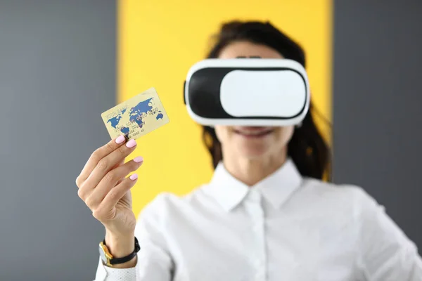 Woman is wearing virtual reality glasses in her hands she is holding bank credit card