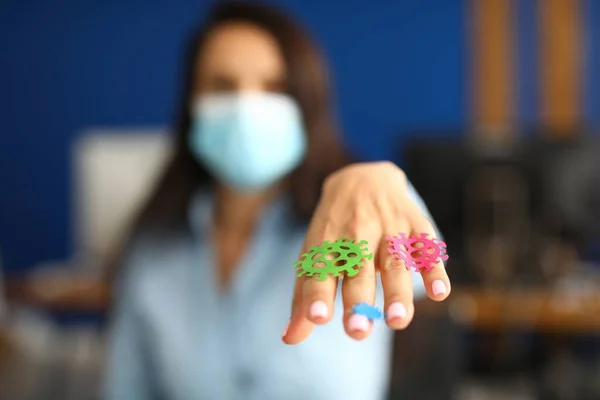 Woman in mask stretches out her hand on which stickers of bacteria are pasted.