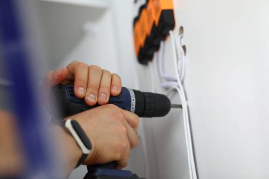 Erkek eller yumruk makinesini tutar ve kabloların yanındaki dolapta delik açar.