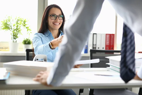 Mujer sonriente en la mesa de trabajo se comunica con su colega — Foto de Stock