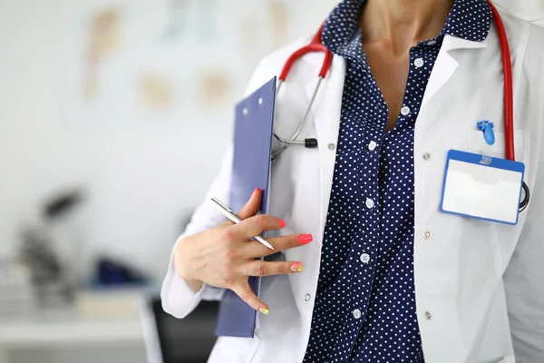 Medico in cappotto bianco sagomato con stetoscopio portablocco e penna in mano — Foto Stock