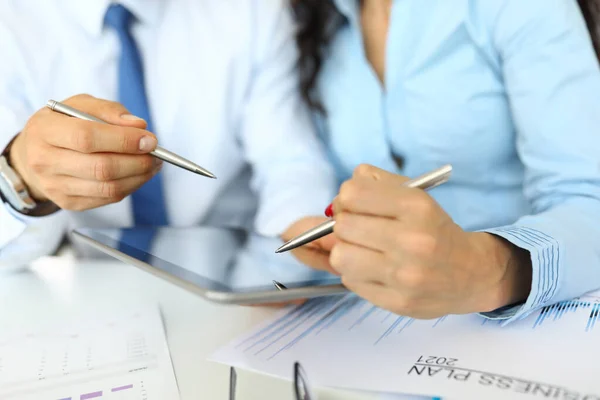 Empresario y mujer de negocios están sosteniendo bolígrafos y tabletas en la mesa de trabajo. — Foto de Stock