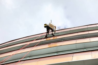 Tırmanışçı binanın iplerine asılıyor.