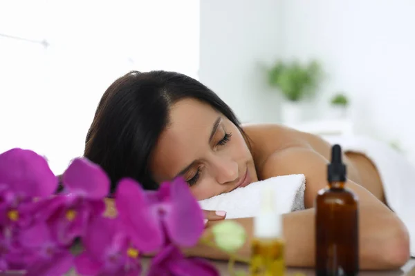 Woman with closed eyes lies on massage table in spa salon — Stock Photo, Image