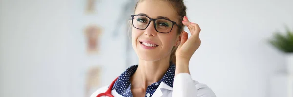 Jeune belle femme souriante médecin dans des lunettes avec stéthoscope autour de son portrait du cou — Photo