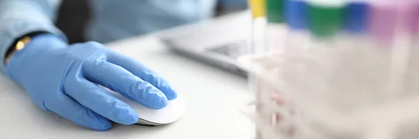Женщина в резиновой перчатке держит компьютерную мышь в химической лаборатории крупным планом — стоковое фото