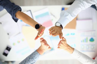 Çalışma masasındaki iş adamları el ele tutuşuyorlar..