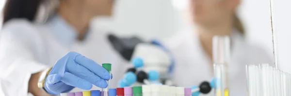 Vrouwen wetenschappers houden glazen reageerbuizen in handschoenen in chemisch laboratorium close-up — Stockfoto