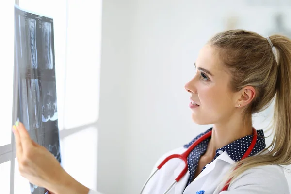 Médico femenino mira una radiografía en el consultorio médico. — Foto de Stock