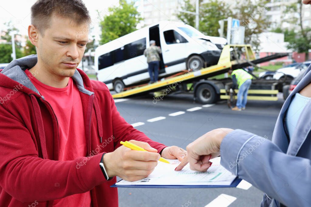Insurance agent gives driver to sign documents after accident.