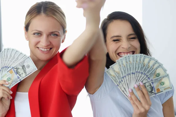 Zwei lächelnde Geschäftsfrauen halten amerikanische Scheine in der Hand. — Stockfoto