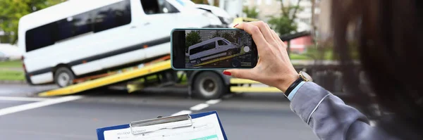 Kvinna försäkring agent filmer trasiga minibuss på smartphone — Stockfoto