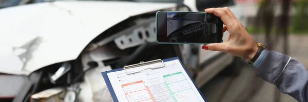 Mujer fotografía un coche roto en el teléfono inteligente y tiene documentos de seguro en sus manos — Foto de Stock