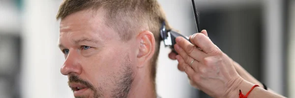 Portrait de l'homme qui a la coupe de cheveux avec machine à écrire dans le salon de coiffure. — Photo