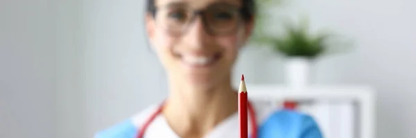Χαμογελαστή γυναίκα γιατρός κρατώντας κόκκινο μολύβι στο χέρι της. — Φωτογραφία Αρχείου