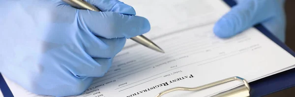 Rękawiczka trzyma schowek i długopis i wypełnia formularz rejestracyjny pacjenta — Zdjęcie stockowe