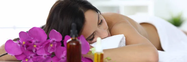 Woman lies with closed eyes on massage table in spa center — Stock Photo, Image