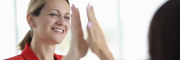 Sorrindo bela mulher loira em jaqueta vermelha dá cinco para outra mulher — Fotografia de Stock