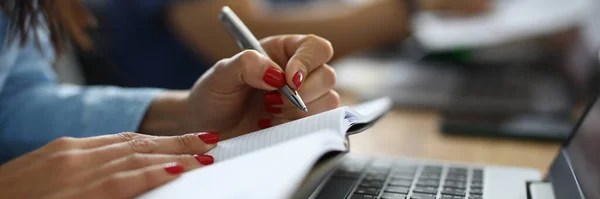 Женщины держат ручку и дневник рядом с ноутбуком за рабочим столом. — стоковое фото