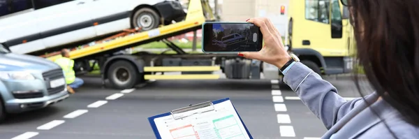Kvinna agent fyller i en försäkring efter bilolycka och skjuter en video på en smartphone. — Stockfoto