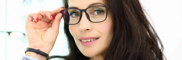 Retrato de mujer sonriente en gafas sobre fondo de escaparate con óptica. —  Fotos de Stock