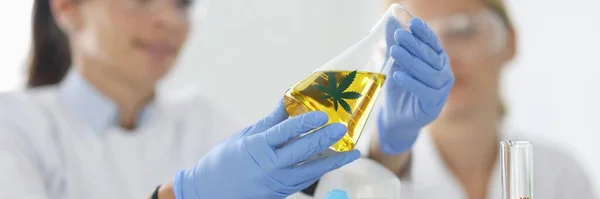 Onderzoeker met bril houdt reageerbuis met marihuana vast. — Stockfoto
