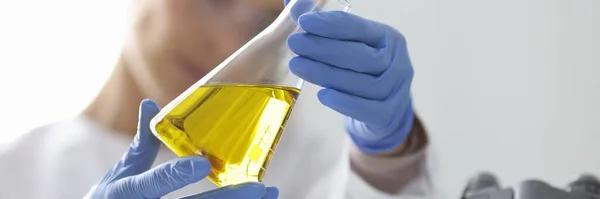 장갑낀 과학자 가황 금빛 액체 플라스크를 들고 있다 스톡 사진
